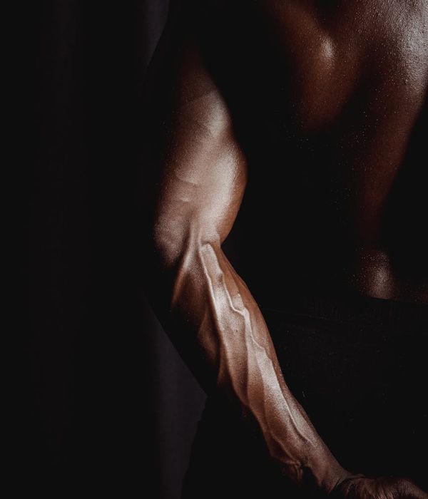 Man performing a strength exercise with intense focus in a dark gym.
